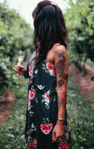 Femme avec un verre de champagne dans un jardin qui porte une robe d'été avec des motifs à fleurs