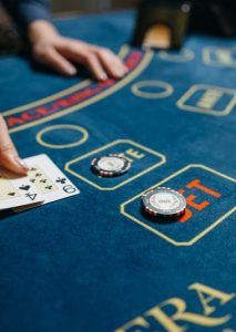 une table de black jack avec des mises de jetons et des cartes retournées par les mains d'un croupier