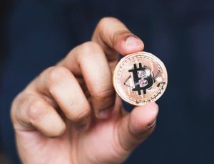 Une main qui tient et présente une cryptomonnaie, un bitcoin