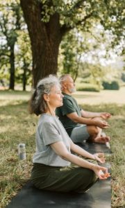 deux seniors entrain de pratiquer le yoga en plein air