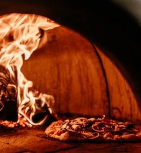 un four à pizza au feu de bois avec une pizza entrain de cuire