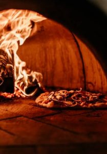 une pizza Margherita entrain de cuire dans un four a pizza avec des flammes
