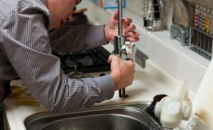 Un homme qui tente de réparer un évier bouché