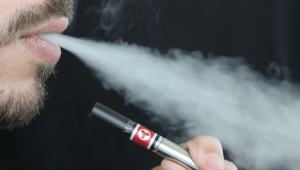 Un homme qui souffle une bouffé d'e-liquide Francais