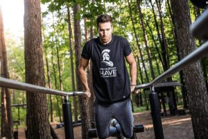 dans un bois un homme en t-shirt noir au barres parallèle sur un Street Workout