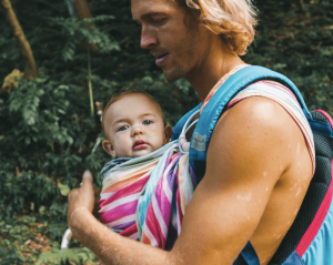 un bébé dans une écharpe de portage avec son papa